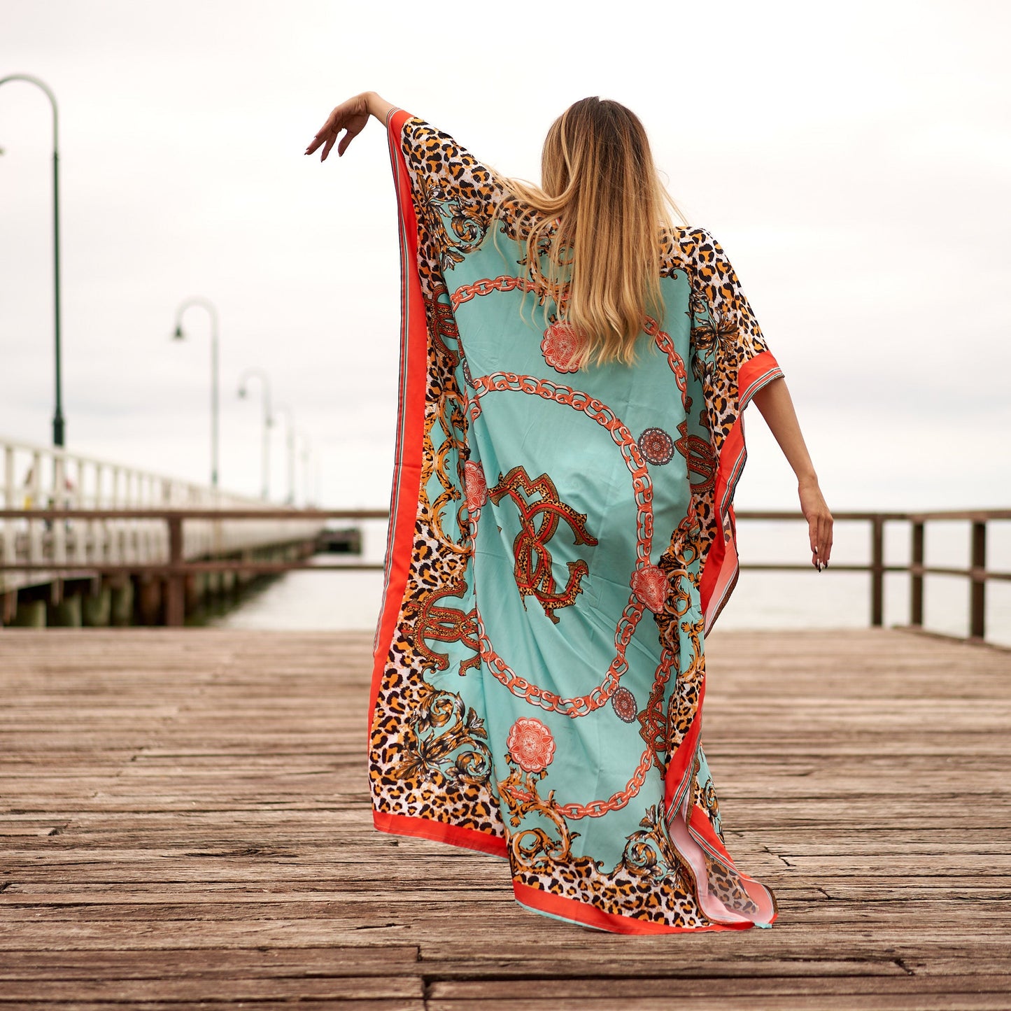 Woman in vibrant floral silk kaftan with side slit

