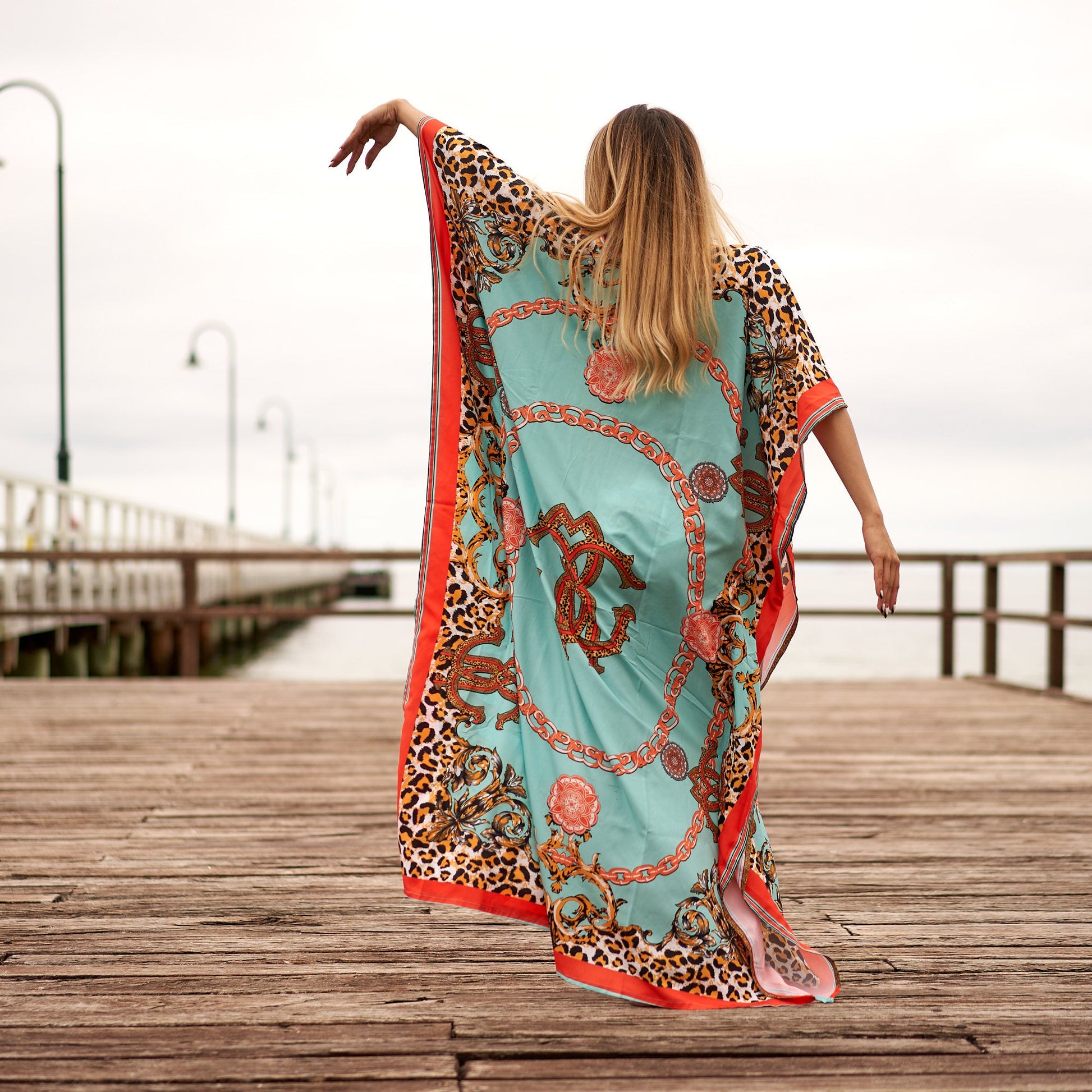 Woman in vibrant floral silk kaftan with side slit
